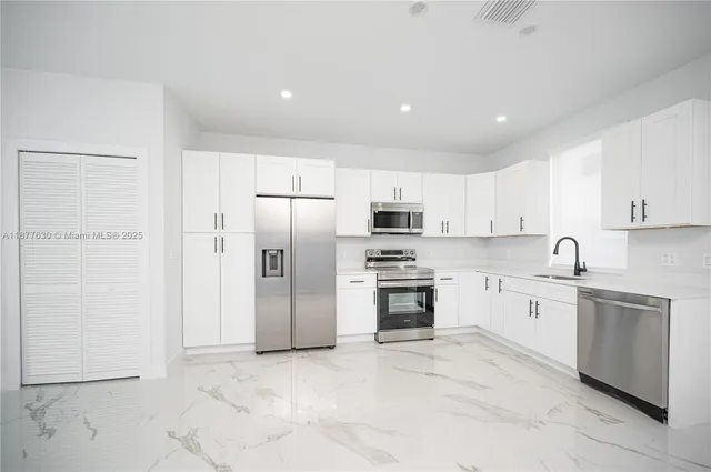 a kitchen with stainless steel appliances a refrigerator sink and stove