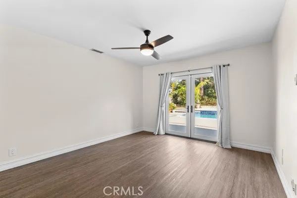 an empty room with wooden floor fan and windows