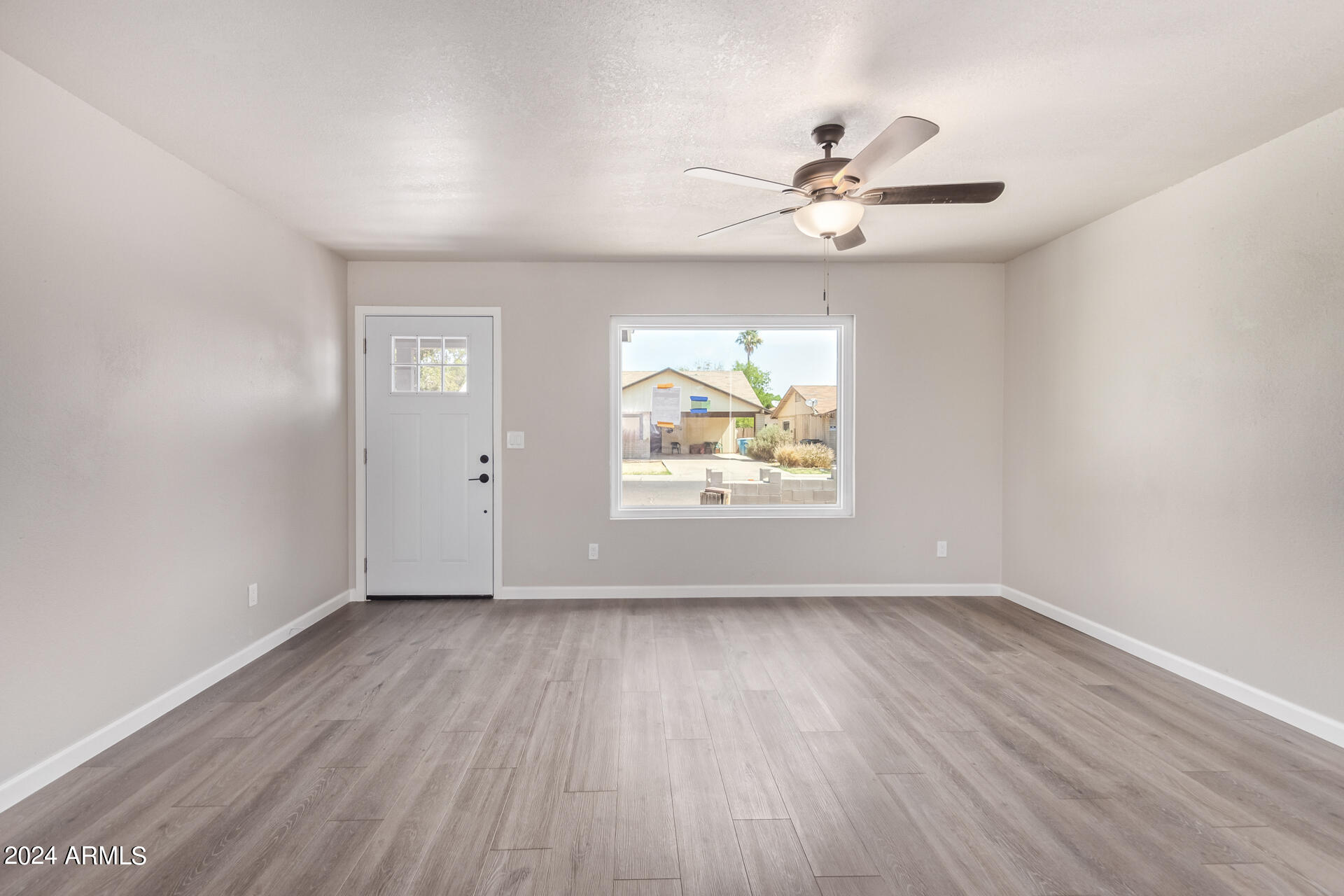 7231 West Flower Street Phoenix, AZ 85033 - Photo 7 of 22 an empty room with wooden floor chandelier fan and windows