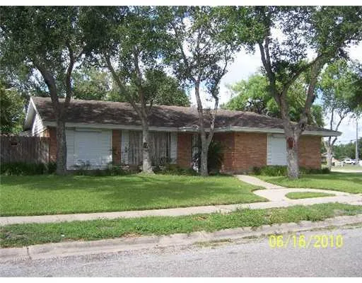 a brick house next to a yard with a large tree