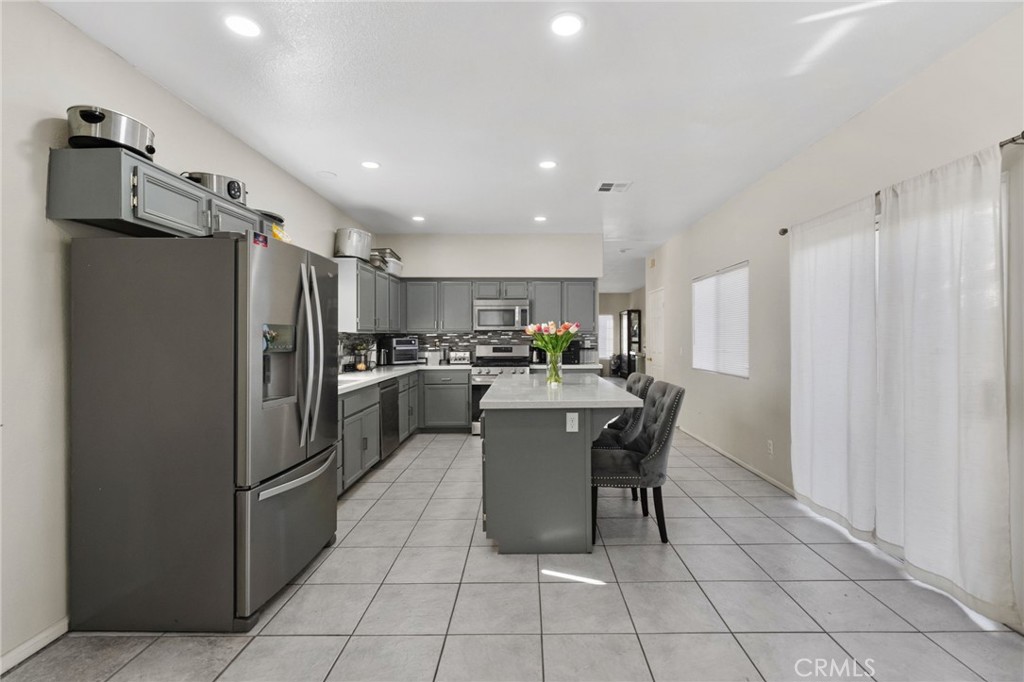 1494 Rabbit Peak Way Hemet, CA 92545 - Photo 16 of 45 a kitchen with a refrigerator a microwave and a dining table