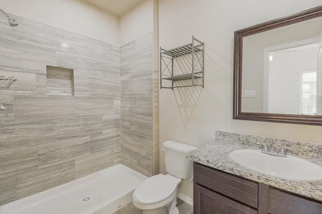 a bathroom with a granite countertop sink a toilet and shower