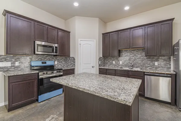 a kitchen with kitchen island granite countertop wooden cabinets and stainless steel appliances