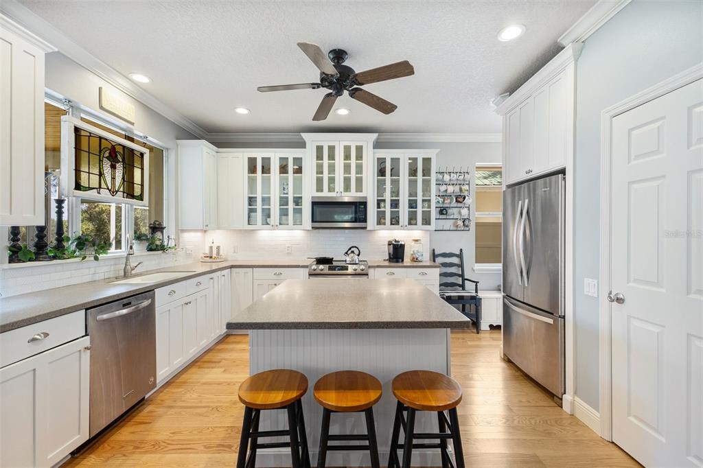 18725 South Obrien Road Groveland, FL 34736 - Photo 34 of 68 a kitchen with stainless steel appliances granite countertop a refrigerator a sink dishwasher a dining table and chairs with wooden floor