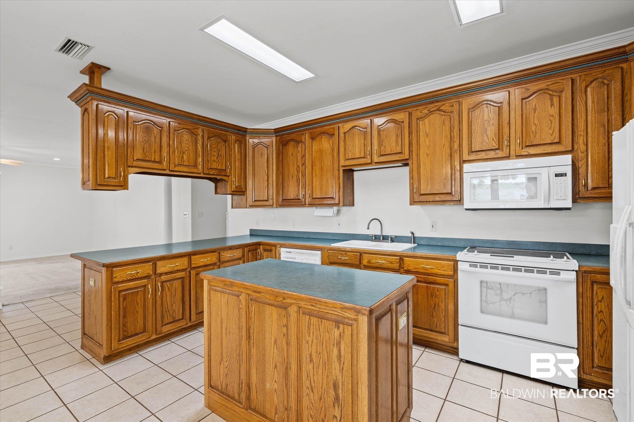 41923 Bayou Road Bay Minette, AL 36507 - Photo 7 of 35 Kitchen featuring wood cabinetry, an integrated island, white tile flooring, and white appliances