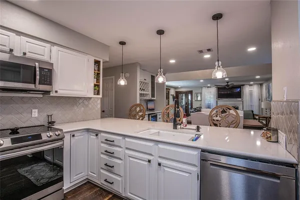 a kitchen with stainless steel appliances kitchen island granite countertop a sink a stove and a microwave
