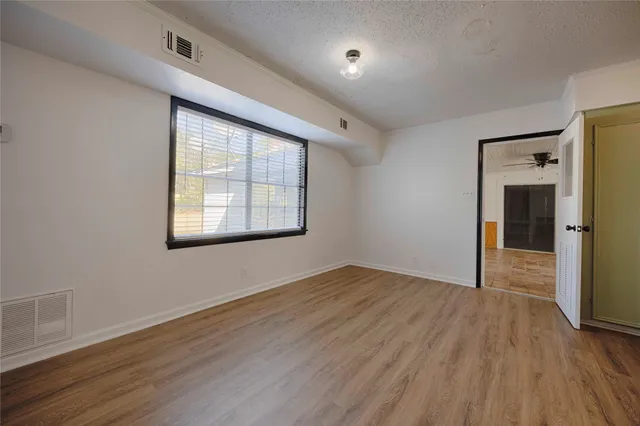 an empty room with wooden floor closet and windows