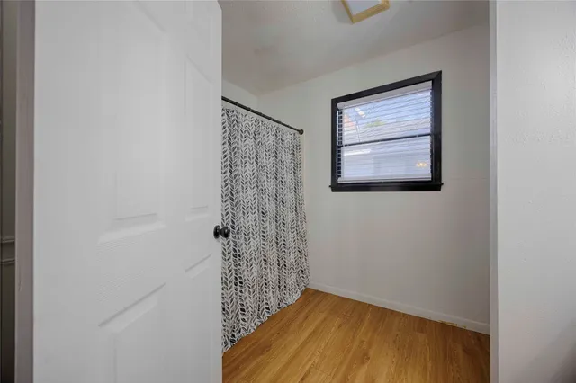 a view of a hallway with wooden floor and a window
