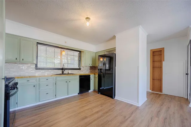 a large kitchen with granite countertop a stove a sink dishwasher a refrigerator and a stove with wooden floor