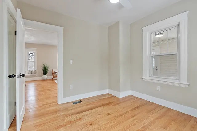 an empty room with wooden floor cabinet and windows