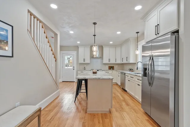 a kitchen with white cabinets stainless steel appliances and wooden floor