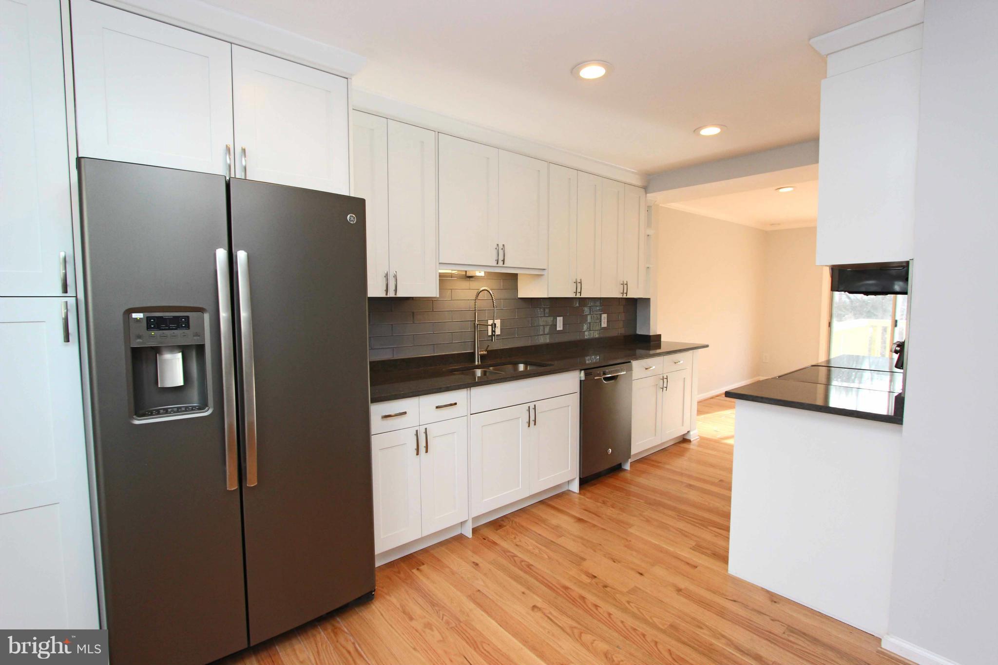a kitchen with stainless steel appliances kitchen island granite countertop a refrigerator a sink and a stove