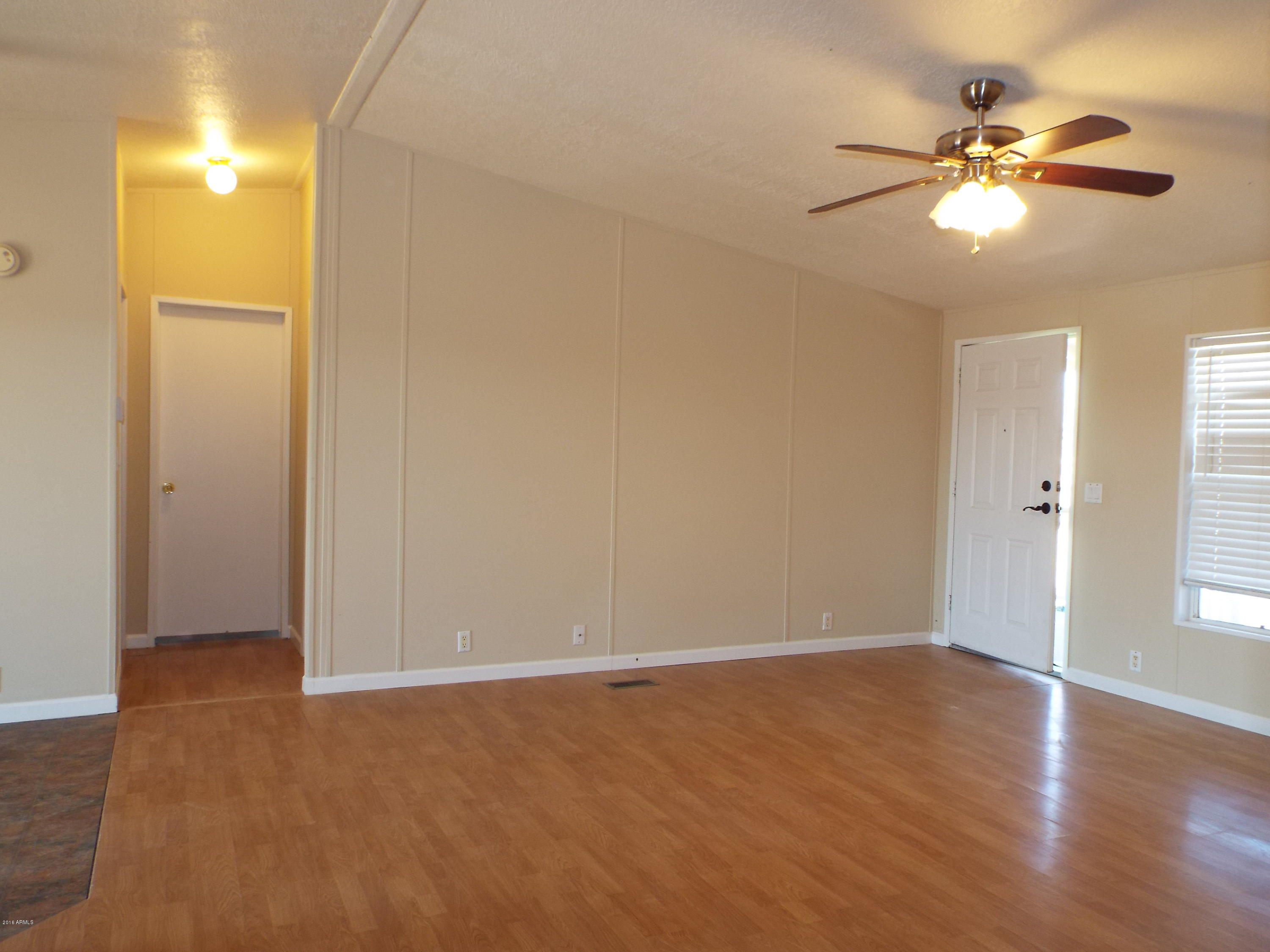 20843 West Teepee Road Buckeye, AZ 85326 - Photo 4 of 29 an empty room with wooden floor fan and windows