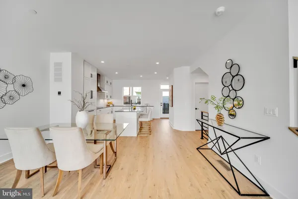 a large kitchen with kitchen island a sink a stove a refrigerator and white cabinets with wooden floor