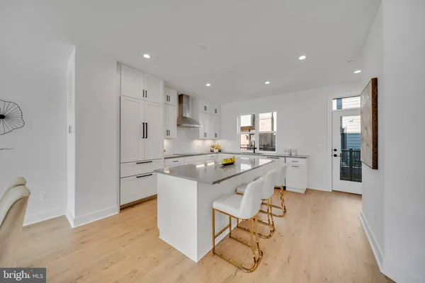 a kitchen with stainless steel appliances kitchen island granite countertop a stove a sink a dining table and chairs with wooden floor