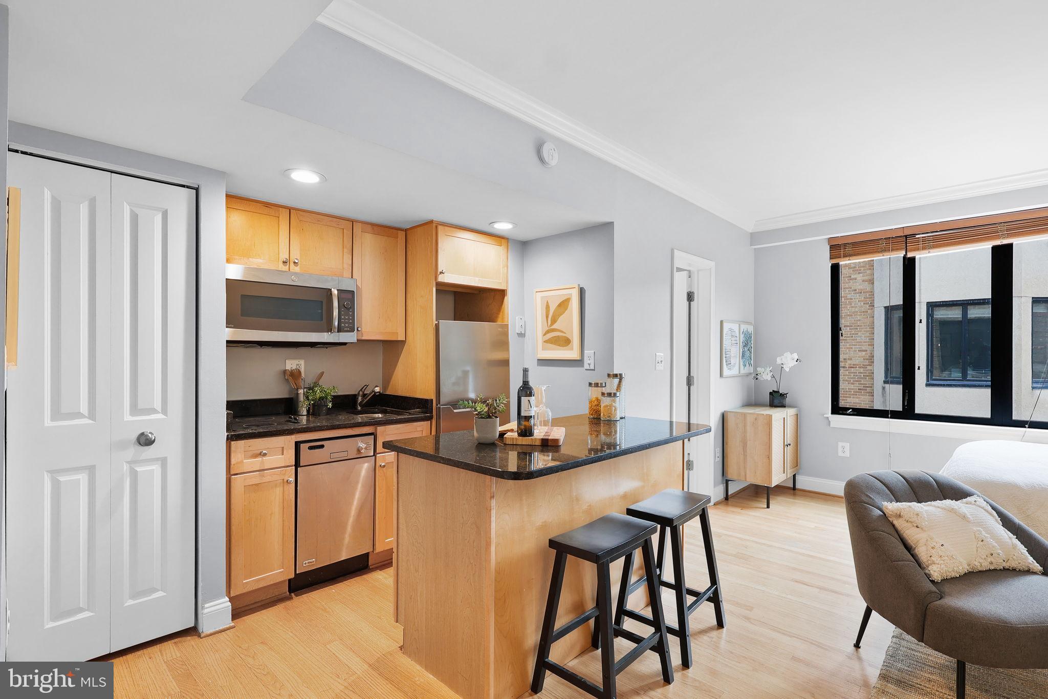 1701 16th Street Northwest, Unit 706 Washington, DC 20009 - Photo 2 of 29 a kitchen with stainless steel appliances granite countertop a stove top oven a sink a dining table and chairs with wooden floor