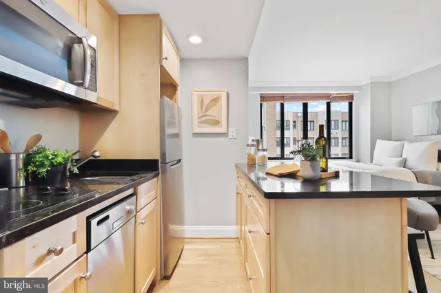 a kitchen with stainless steel appliances granite countertop a sink a stove and a wooden floor