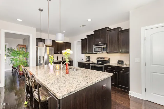 a kitchen with stainless steel appliances granite countertop a stove a refrigerator a kitchen island a sink and chairs
