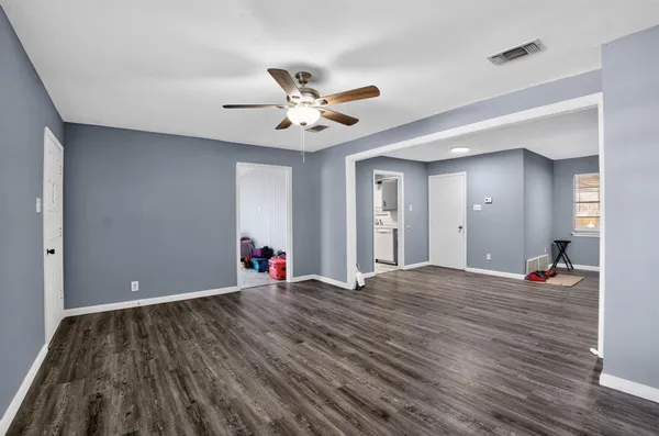 a view of an empty room with wooden floor and a ceiling fan
