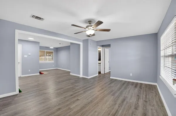 a view of an empty room with window and wooden floor