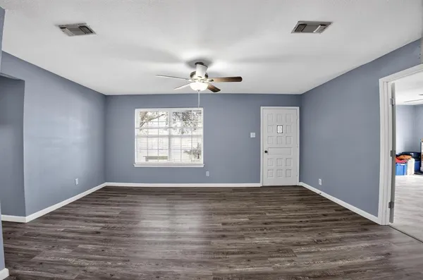 a view of an empty room with window and wooden floor