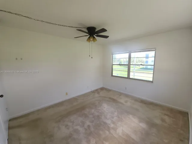 an empty room with windows and chandelier fan