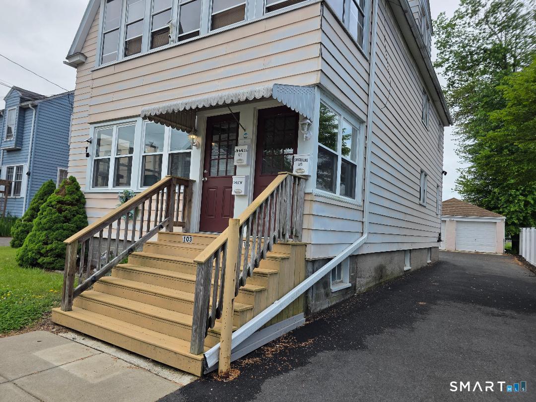 a view of a house with wooden stairs and a small yard