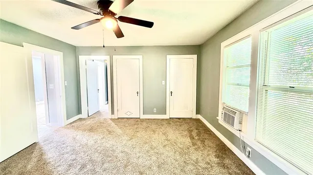 a view of a big room with windows and chandelier fan