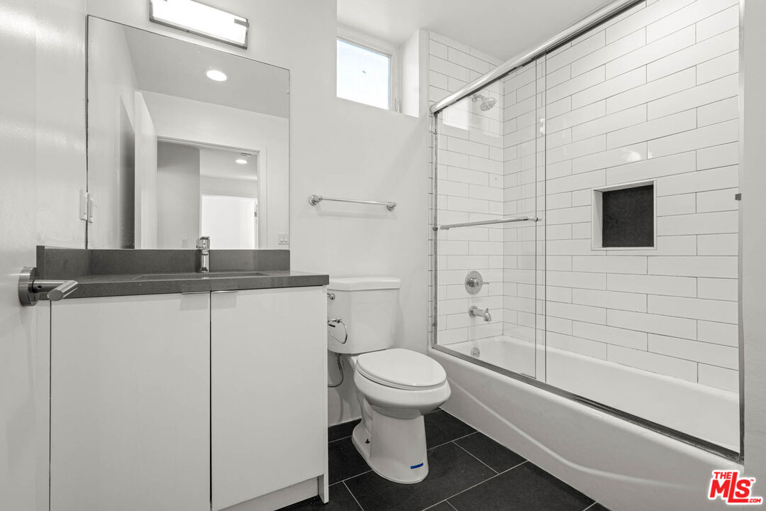 1215 South Bedford Street, Unit 105 Los Angeles, CA 90035 - Photo 16 of 27 a bathroom with a granite countertop sink toilet and shower