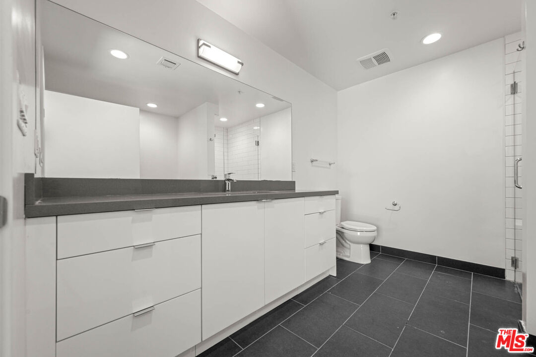 1215 South Bedford Street, Unit 105 Los Angeles, CA 90035 - Photo 17 of 27 a bathroom with a toilet a sink and mirror