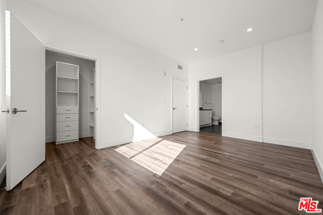 1215 South Bedford Street, Unit 105 Los Angeles, CA 90035 - Photo 19 of 27 a view of an empty room with wooden floor and closet