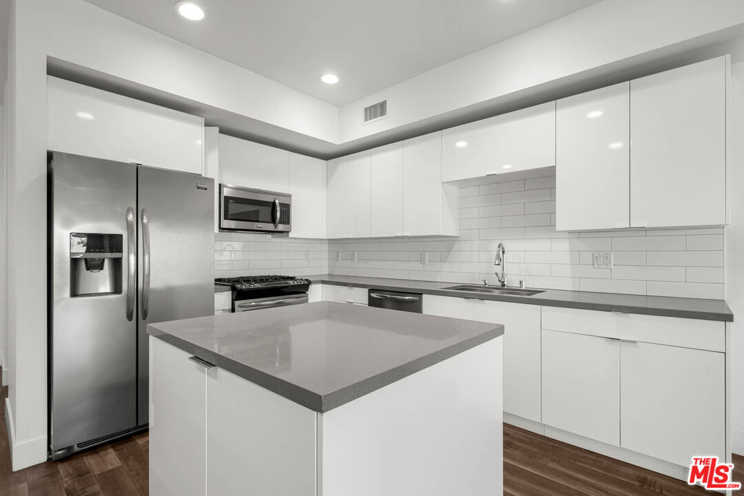 1215 South Bedford Street, Unit 105 Los Angeles, CA 90035 - Photo 2 of 27 a kitchen with a center island and stainless steel appliances