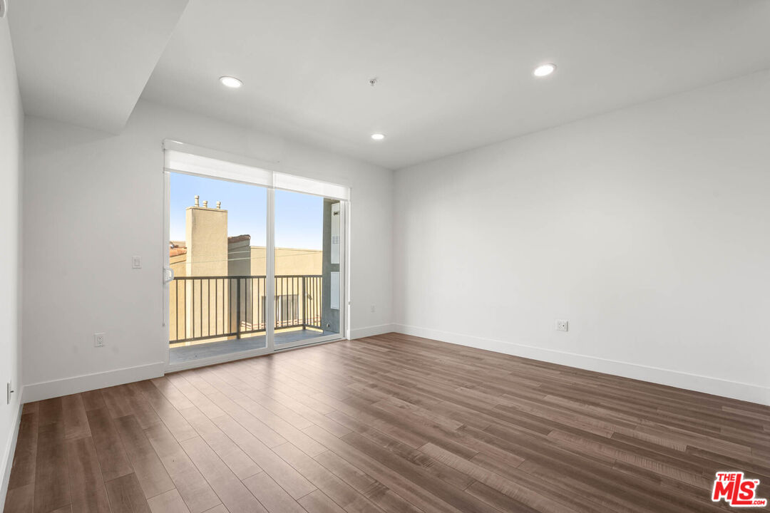 1215 South Bedford Street, Unit 105 Los Angeles, CA 90035 - Photo 6 of 27 a view of an empty room with wooden floor and a window