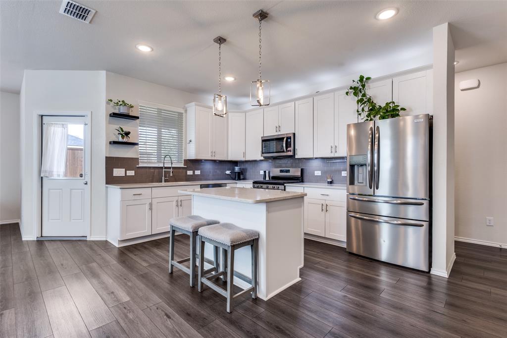 1810 Hummingbird Street Princeton, TX 75407 - Photo 11 of 25 a kitchen with white cabinets and stainless steel appliances