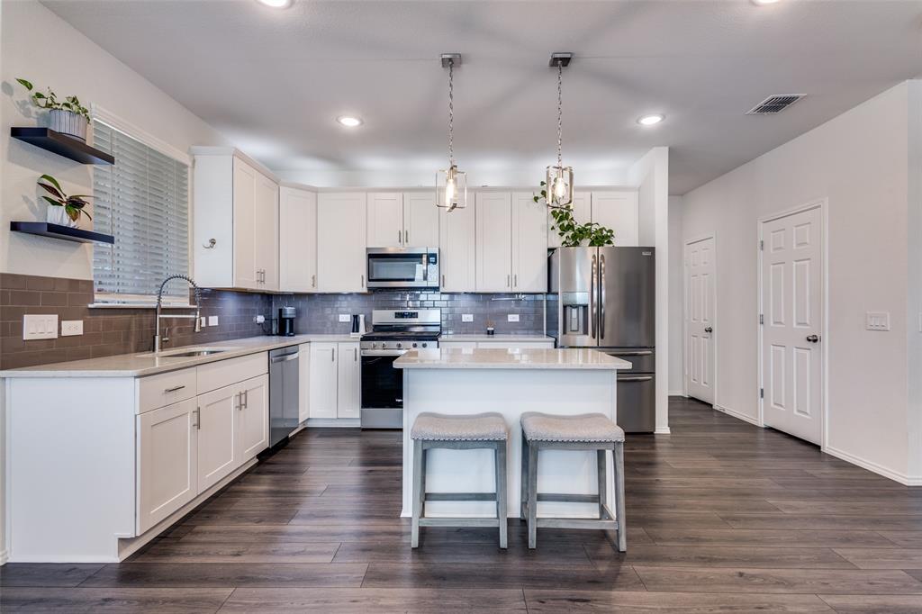 1810 Hummingbird Street Princeton, TX 75407 - Photo 12 of 25 a kitchen with white cabinets stainless steel appliances and kitchen island