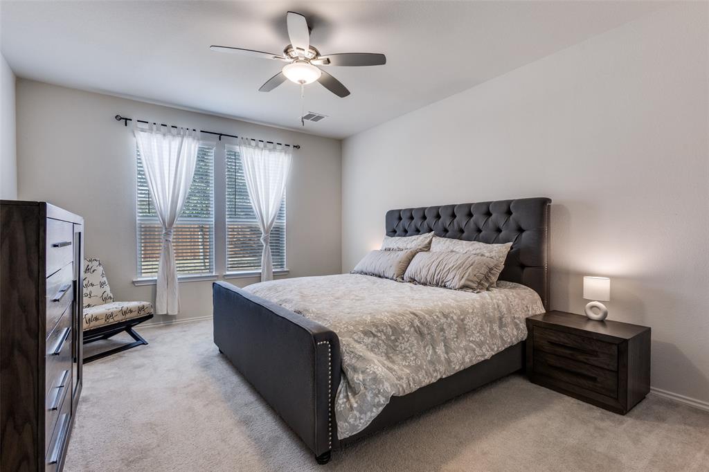 1810 Hummingbird Street Princeton, TX 75407 - Photo 16 of 25 a spacious bedroom with a bed a chandelier and a couch