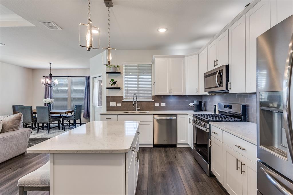 1810 Hummingbird Street Princeton, TX 75407 - Photo 9 of 25 a kitchen with stainless steel appliances kitchen island granite countertop a stove top oven a sink a center island and cabinets