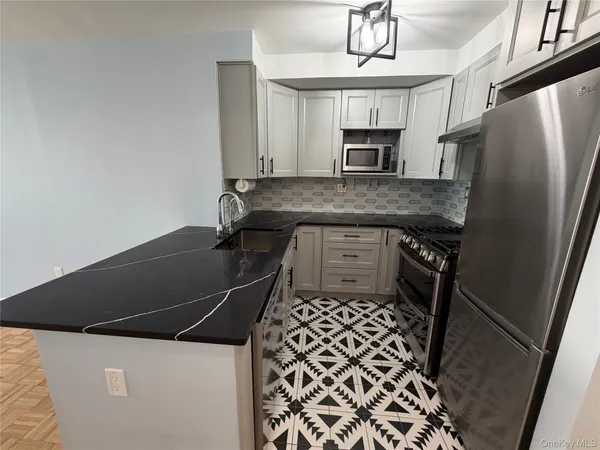 a kitchen with granite countertop a refrigerator a stove and white cabinets