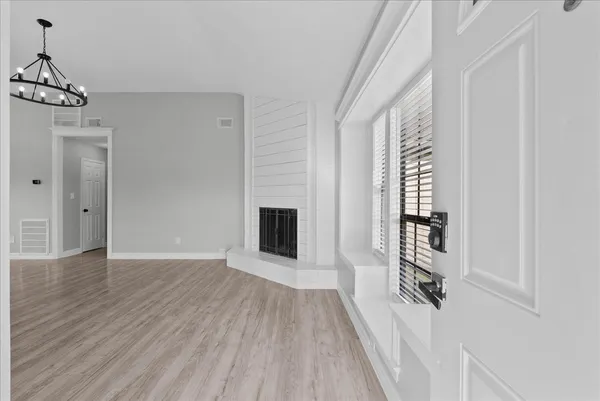 a view of an empty room with wooden floor fireplace and a window