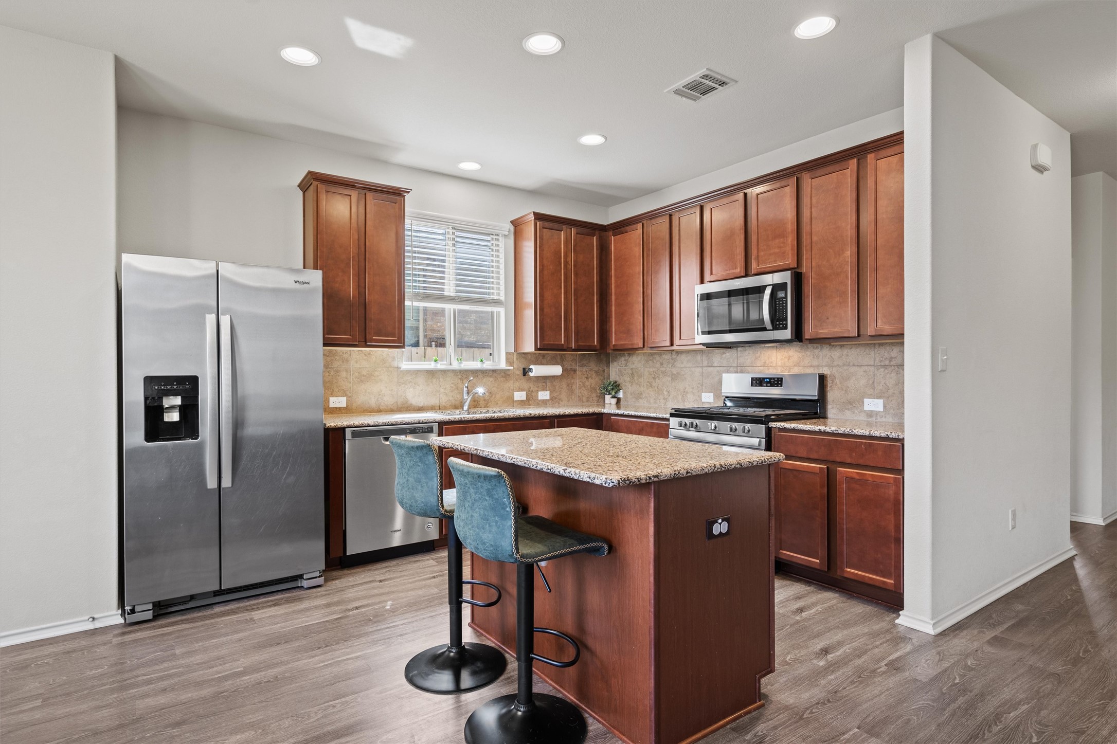 11816 Jackson Fls Way Manor, TX 78653 - Photo 12 of 40 a kitchen with stainless steel appliances granite countertop a refrigerator a stove a sink and a microwave