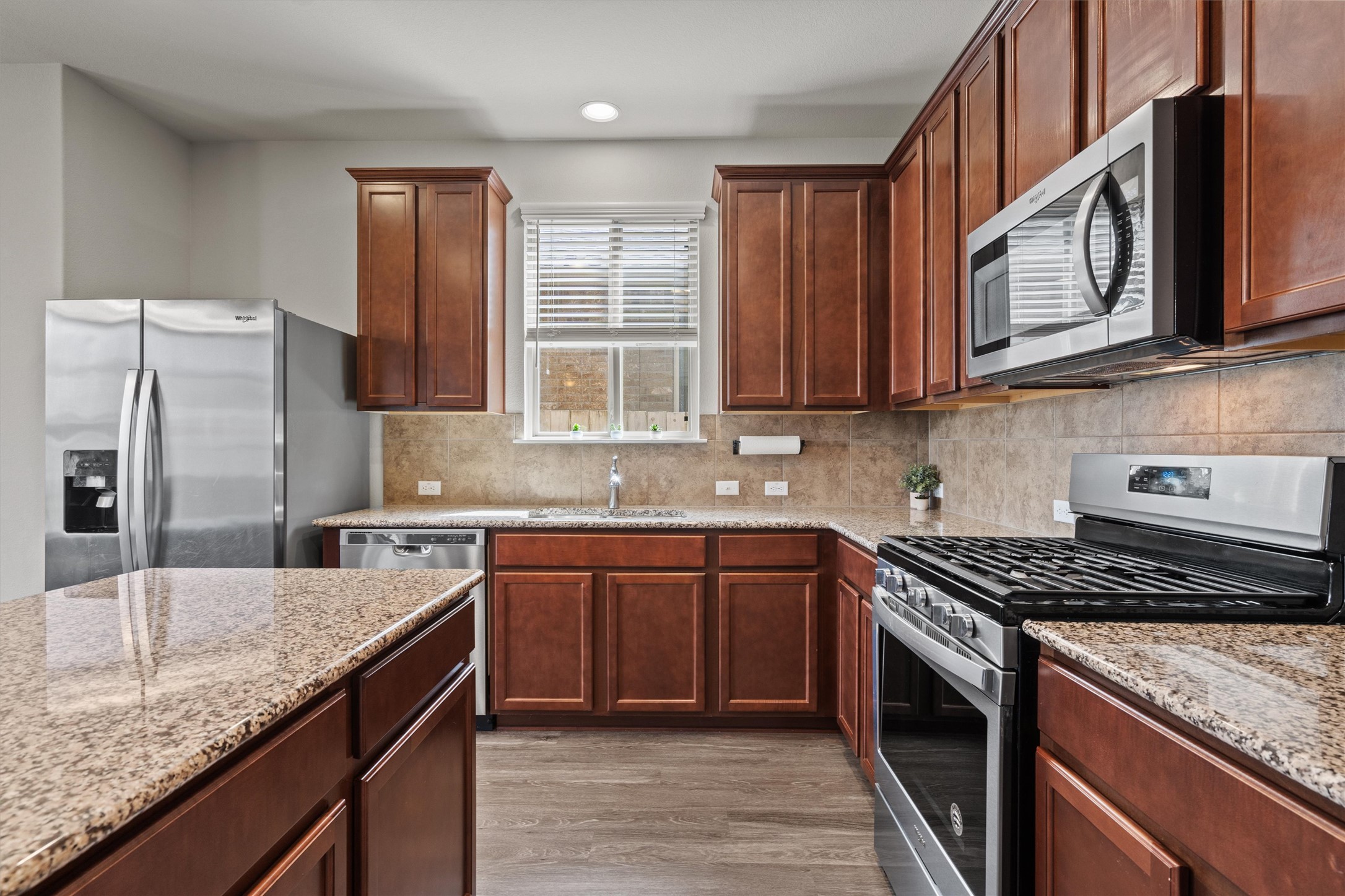 11816 Jackson Fls Way Manor, TX 78653 - Photo 13 of 40 a kitchen with stainless steel appliances granite countertop a stove a sink dishwasher and microwave oven with cabinets