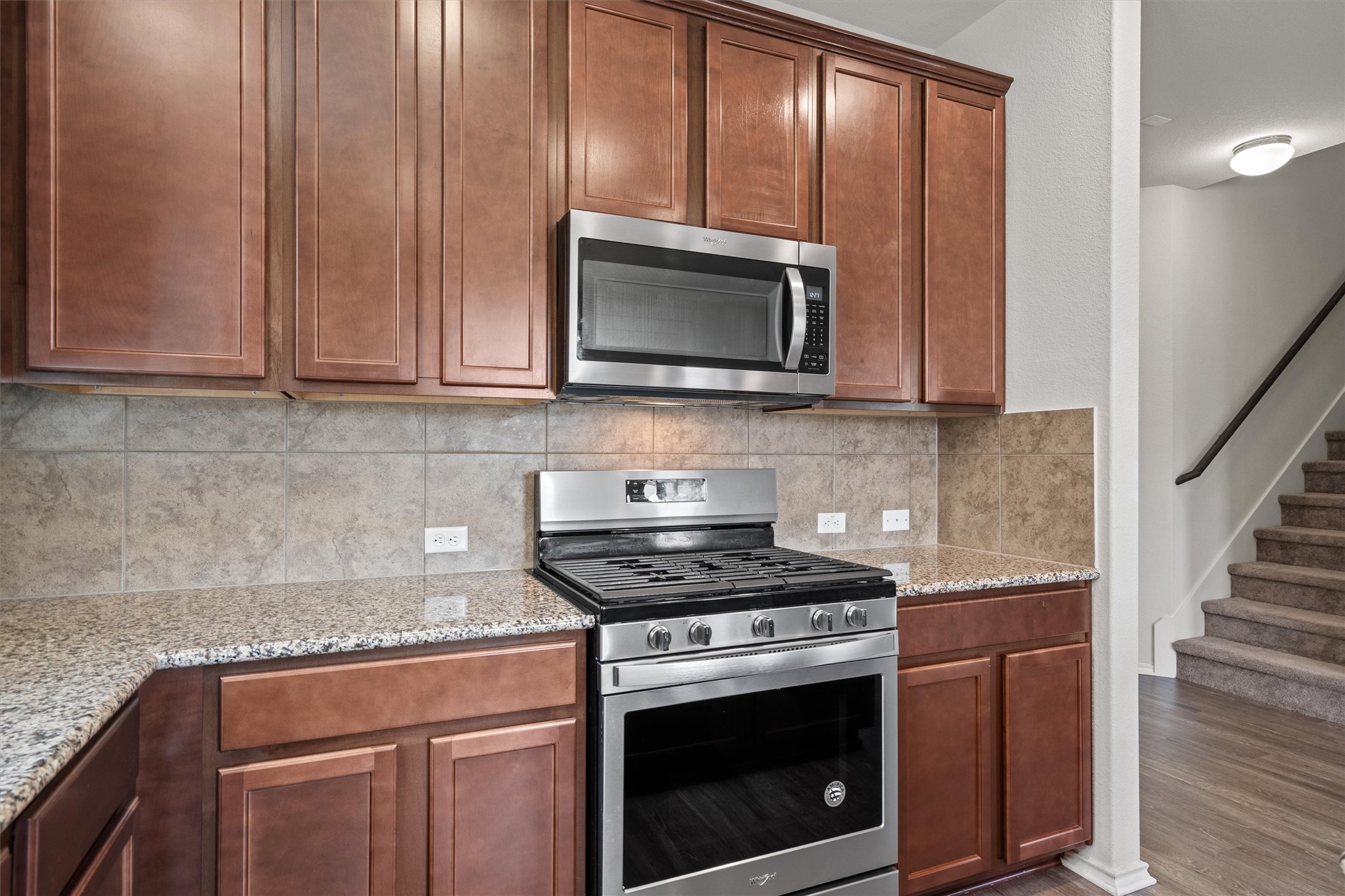 11816 Jackson Fls Way Manor, TX 78653 - Photo 15 of 40 a kitchen with granite countertop wooden cabinets stainless steel appliances and a counter space