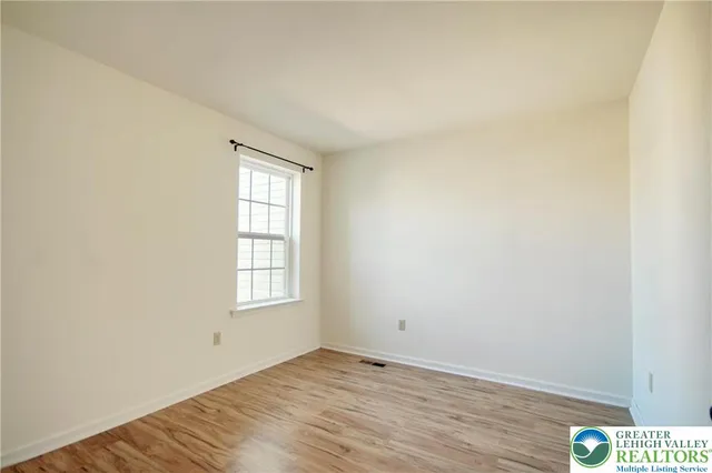 an empty room with wooden floor and window