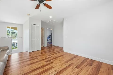 a view of an empty room with wooden floor and a ceiling fan
