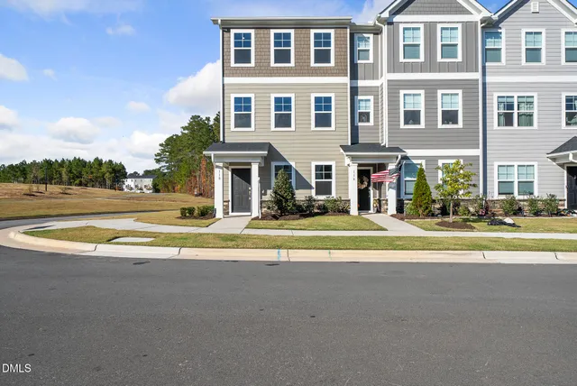 a front view of residential houses with yard and road