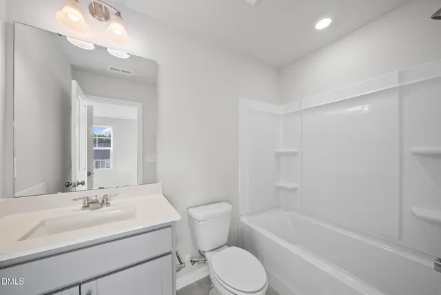 a bathroom with a bathtub shower sink vanity mirror and toilet