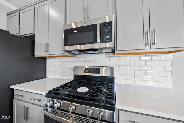a large white kitchen with kitchen island a sink a stove a refrigerator and white cabinets