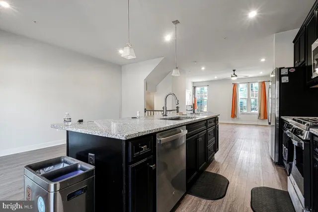 a kitchen with granite countertop a sink a counter top space stainless steel appliances and cabinets