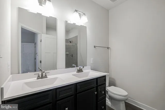 a bathroom with a double vanity sink toilet and a mirror