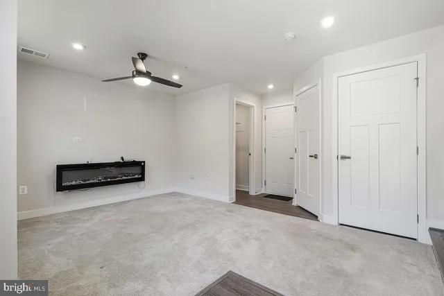 an empty room with chandelier fan and windows